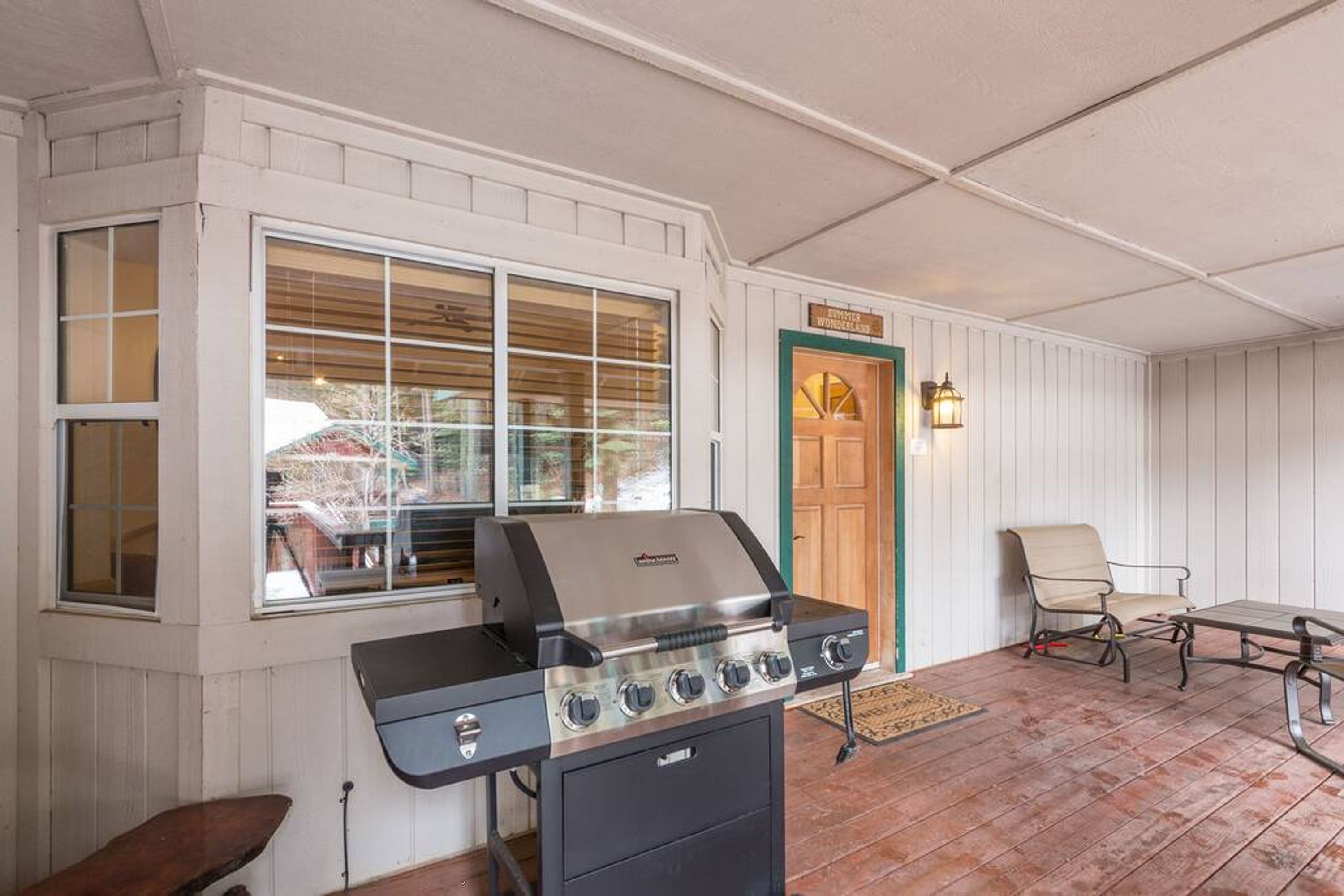 An outdoor patio with a grill, a chair, and a table.