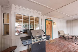 Un patio al aire libre con una parrilla, una silla y una mesa.