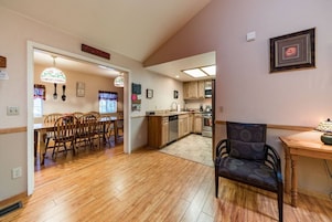 Una cocina amplia con armarios de madera, un comedor con mesa y sillas, y un pasillo que conduce a una sala de estar.
