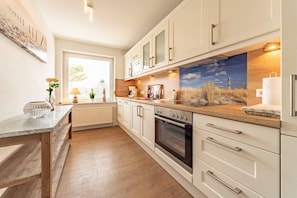 A modern kitchen with white cabinets, a wooden countertop, and a built-in oven. - View of the dike to the right (Norddeich)