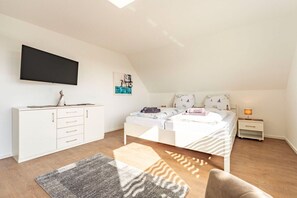 A bedroom with a bed, a TV, a desk, and a nightstand. - View of the dike to the right (Norddeich)
