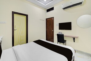 A hotel room with a bed, a desk, a chair, a television, and an air conditioning unit. - Hotel O Venkateswara Swamy Temple (Hyderabad)