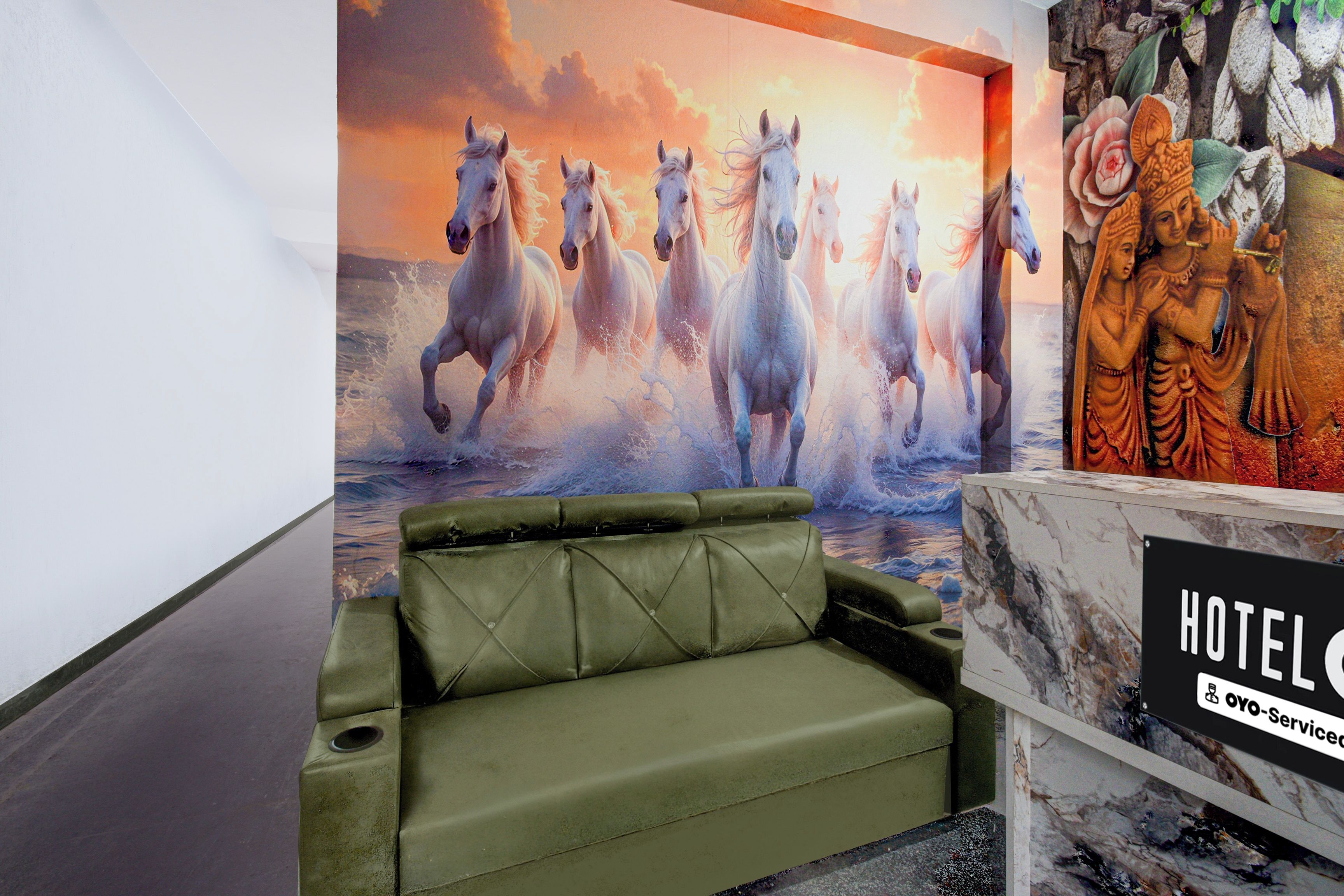 Un hall d’hôtel avec un canapé vert, une grande fresque représentant un cheval et une statue.