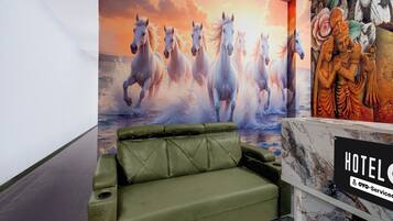 Un hall d’hôtel avec un canapé vert, une grande fresque représentant un cheval et une statue.