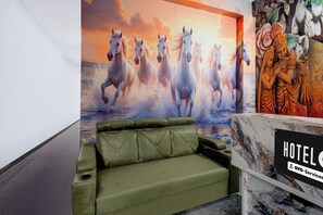 Un hall de hotel con un sofá verde, un mural grande de un caballo y una estatua.