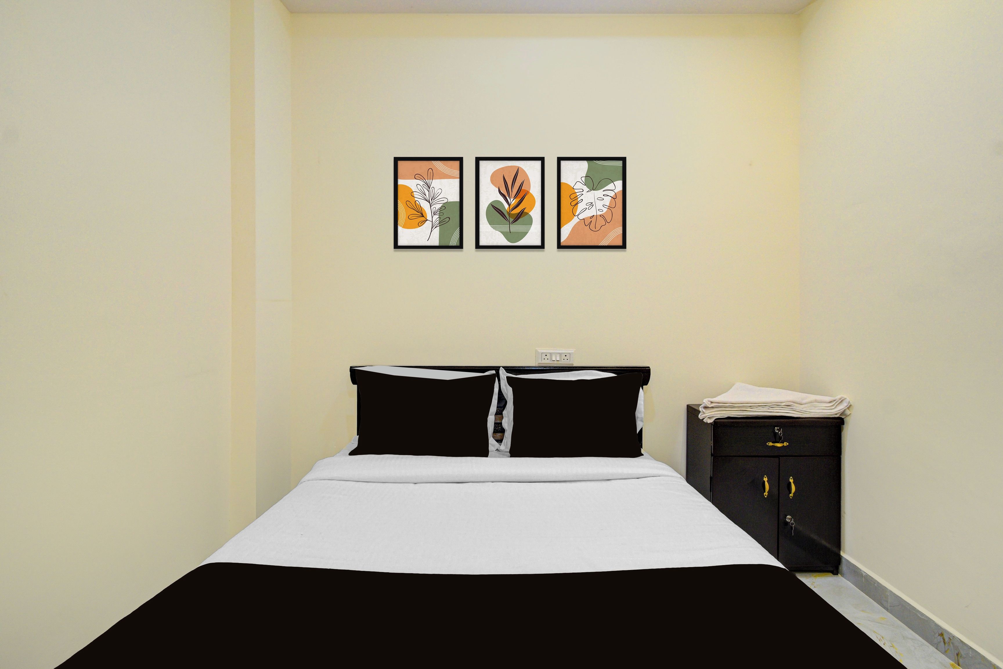 Habitación de hotel con una cama, una mesita de noche y tres obras de arte enmarcadas en la pared.