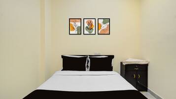 Habitación de hotel con una cama, una mesita de noche y tres obras de arte enmarcadas en la pared.