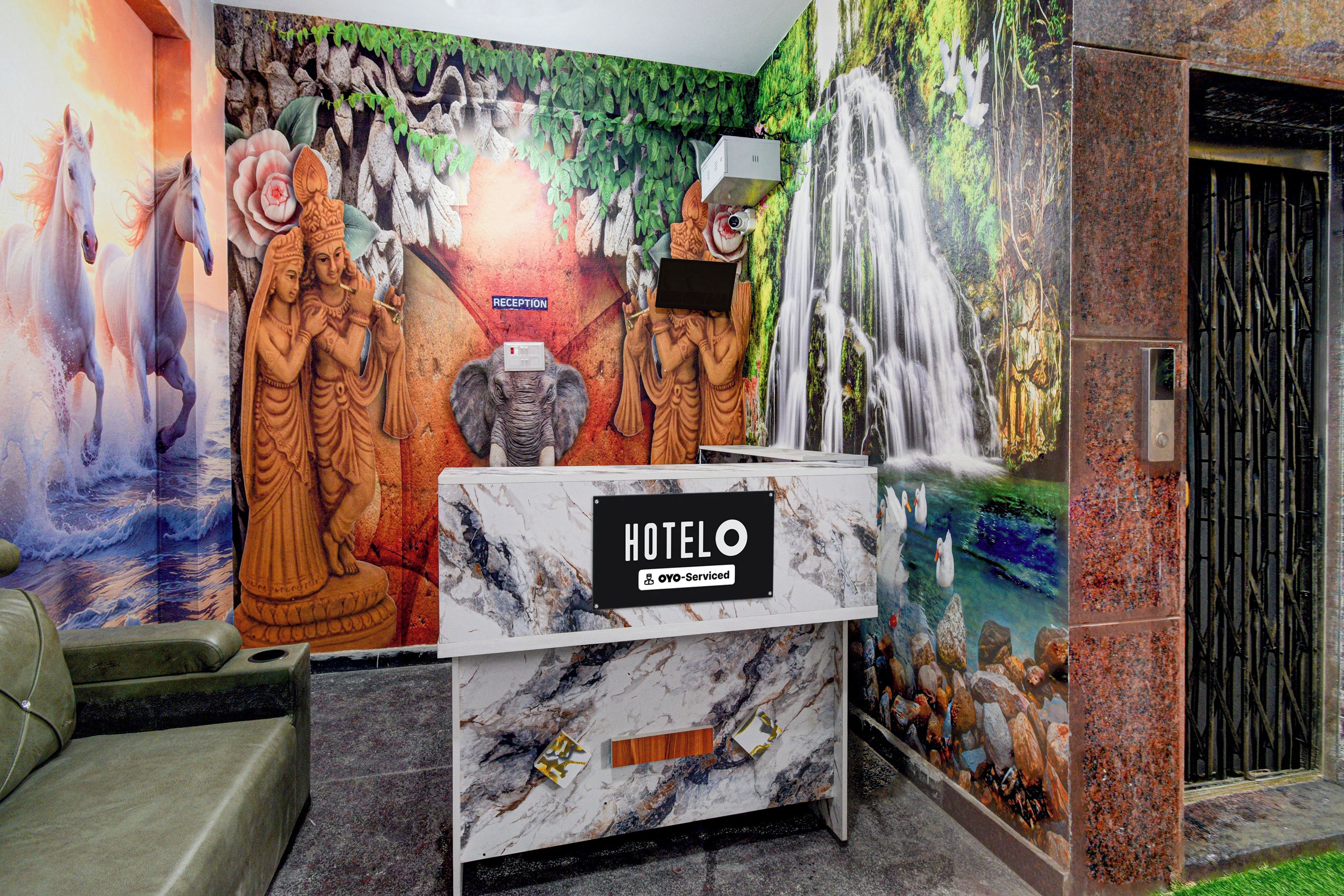 A hotel reception desk with a marble top, a sign indicating 'HOTEL' and 'o-v-serviced', and a mural depicting various figures and a waterfall.