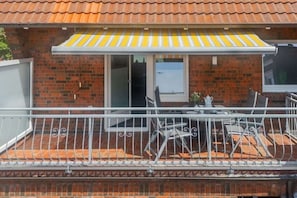 A balcony with a metal railing, a table, and chairs. - Dike view left||Norddeich (Norddeich)