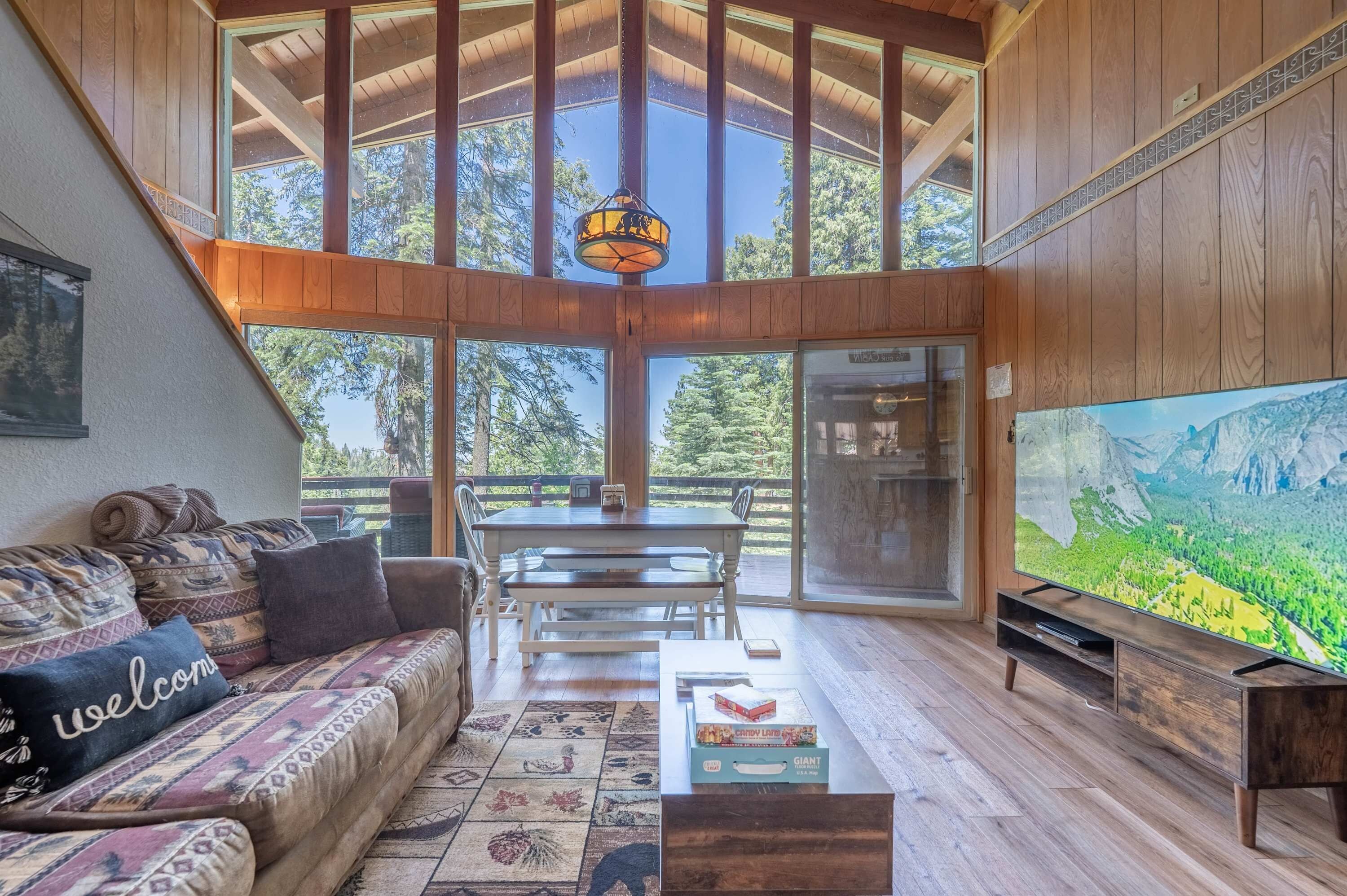 A cozy living room with a wooden ceiling, a large TV, a sofa, and a dining table.