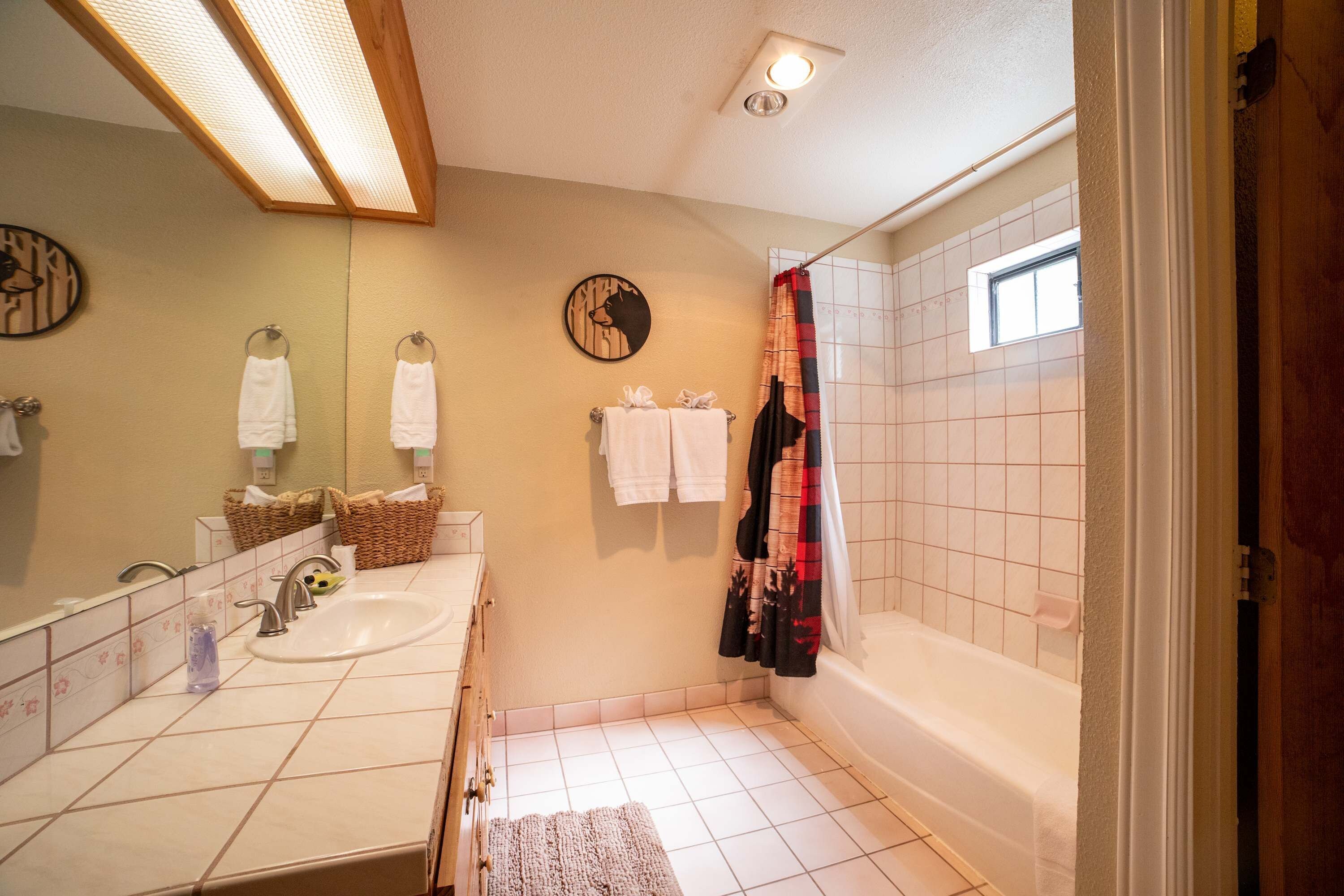 A bathroom with a sink, mirror, and shower.