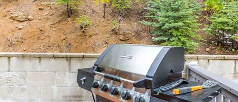 A barbecue grill with a control panel, a spatula, and a grill brush.