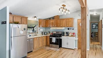 Una cocina con armarios de madera, un refrigerador de acero inoxidable, una estufa y un lavamanos.