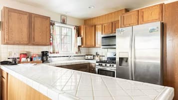 A kitchen with wooden cabinets, a stainless steel refrigerator, a stove, and a microwave.