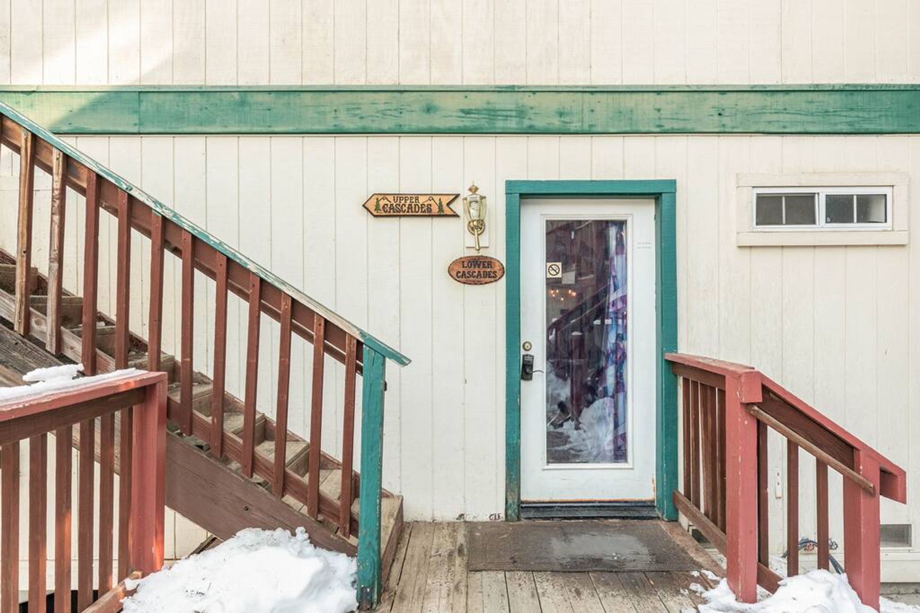 A wooden staircase leading to a door with a sign indicating 'Upper Cascades' and 'Lower Cascades.'