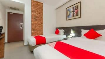 Habitación de hotel con dos camas, una pared de ladrillo decorativa, un cuadro y una puerta.