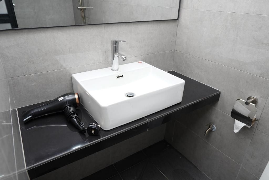 Un baño con lavamanos blanco, un espejo y encimera negra.