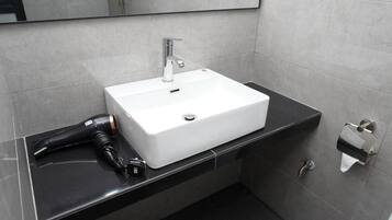 Un baño con lavamanos blanco, un espejo y encimera negra.