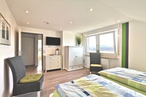 Ein Schlafzimmer mit zwei Betten, einem Fernseher, einem Kleiderschrank, einem Schreibtisch und einem Fenster mit Blick.