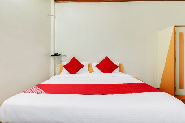 A hotel room with a bed, a telephone, and a door.