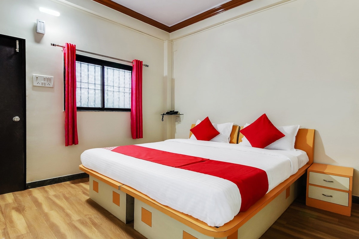 Una habitación de hotel con una cama, una mesita de noche, cortinas y una puerta.