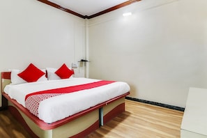 Habitación de hotel con cama, mesita de noche, teléfono en la pared y un interruptor de luz.