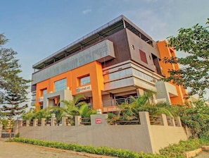 Edifício de vários andares com telhado plano, placa indicando área de estacionamento e entrada com portão.