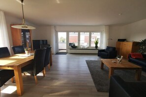 A modern living room with a dining area, large windows, and a view of the outside. - 4 House Achter de Duenen - the space miracle (Norderney)