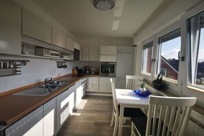 Eine moderne Küche mit weißen Schränken, einer Holzausziehtischplatte und einem Essbereich mit Tisch und Stühlen.
