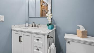 Un baño con un lavamanos de mármol, una puerta de madera, un inodoro y una toalla colgada en la pared.