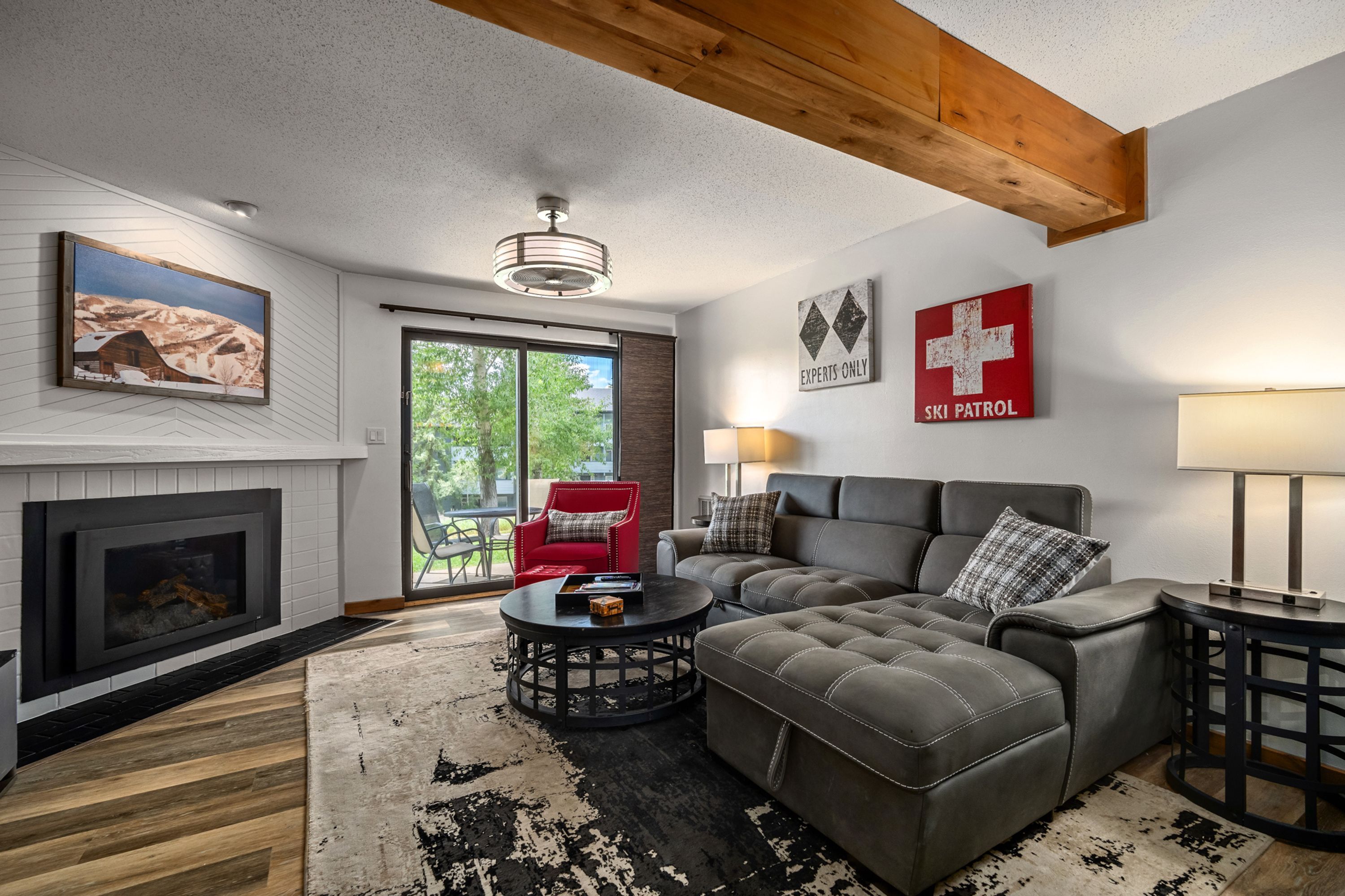 A modern living room with a fireplace, a large sectional sofa, a red armchair, and a dining table.