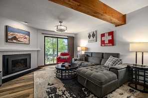 A modern living room with a fireplace, a large sectional sofa, a red armchair, and a dining table. - Hot Tubs and Pool -looping Shuttle- Cozy Fireplace (Steamboat Springs)