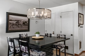 A dining area with a black table, patterned chairs, a chandelier, and a framed picture on the wall. - Hot Tubs and Pool -looping Shuttle- Cozy Fireplace (Steamboat Springs)
