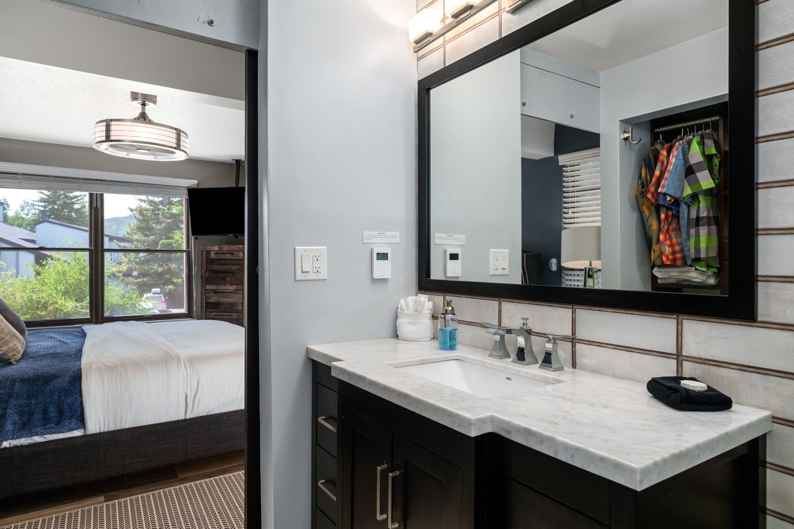 A modern bathroom with a large mirror, a sink, and a window.