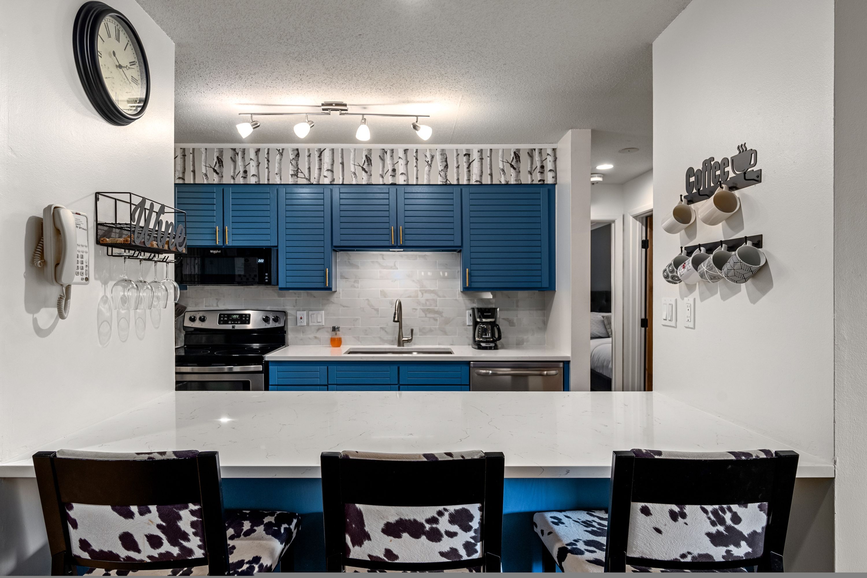Una cocina moderna con armarios azules, una encimera blanca y un comedor con dos sillas.