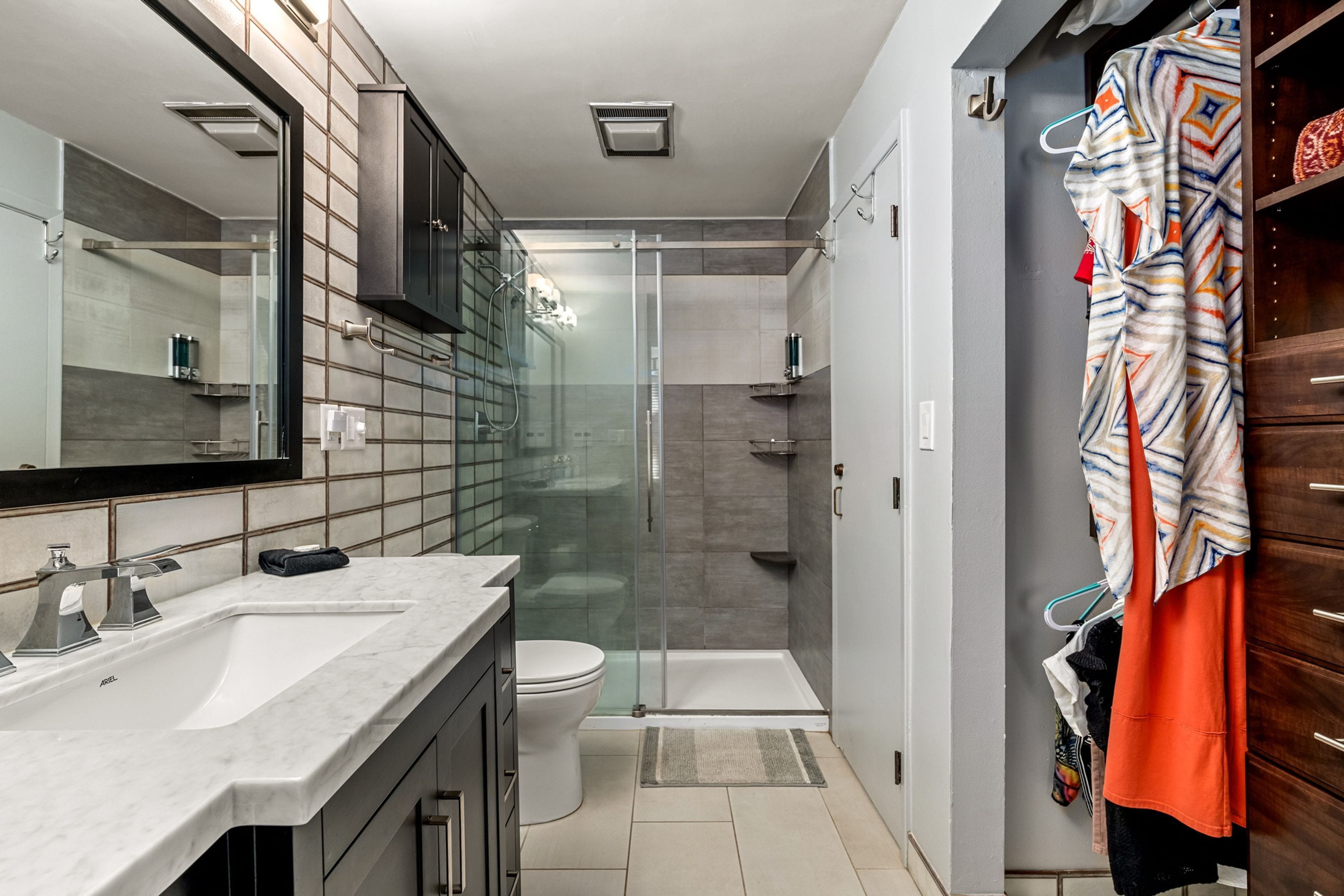 A modern bathroom with a glass shower enclosure, a white toilet, and a marble sink.
