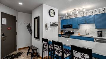 Una cucina moderna con mobili azzurri, un forno a microonde e una sveglia appesa al muro.
