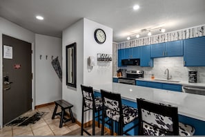 Una cocina moderna con armarios azules, microondas y un reloj en la pared.