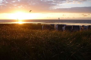 A beach with a sunset, grassy foreground, and beach chairs. - Holiday apartment with 1 bedroom (Norderney)