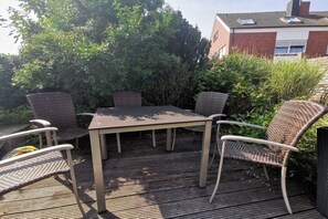 Um pátio externo com uma mesa e quatro cadeiras de vime.