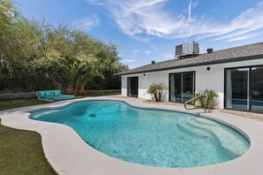 Ein modernes Haus mit Swimmingpool, Terrasse und einem großen Baum.