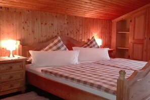 Ein Zimmer aus Holz mit einem Bett, Nachttischen und einem Kleiderschrank.