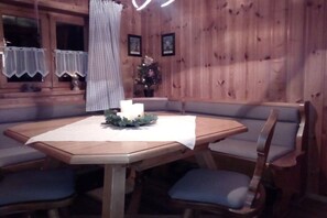 Ein Zimmer mit Holzvertäfelung, einem runden Tisch, gepolsterten Stühlen und einer Bank.