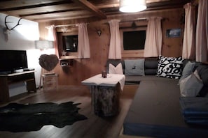 Ein gemütliches Blockhaus-Interieur mit einer Couch, einem Fernseher, einem Tisch mit Herz-Dekoration und rustikalem Ambiente.