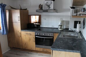Eine Küche mit Holzausstattung, einem Backofen, einer Kaffeemaschine und einem Spülbecken.