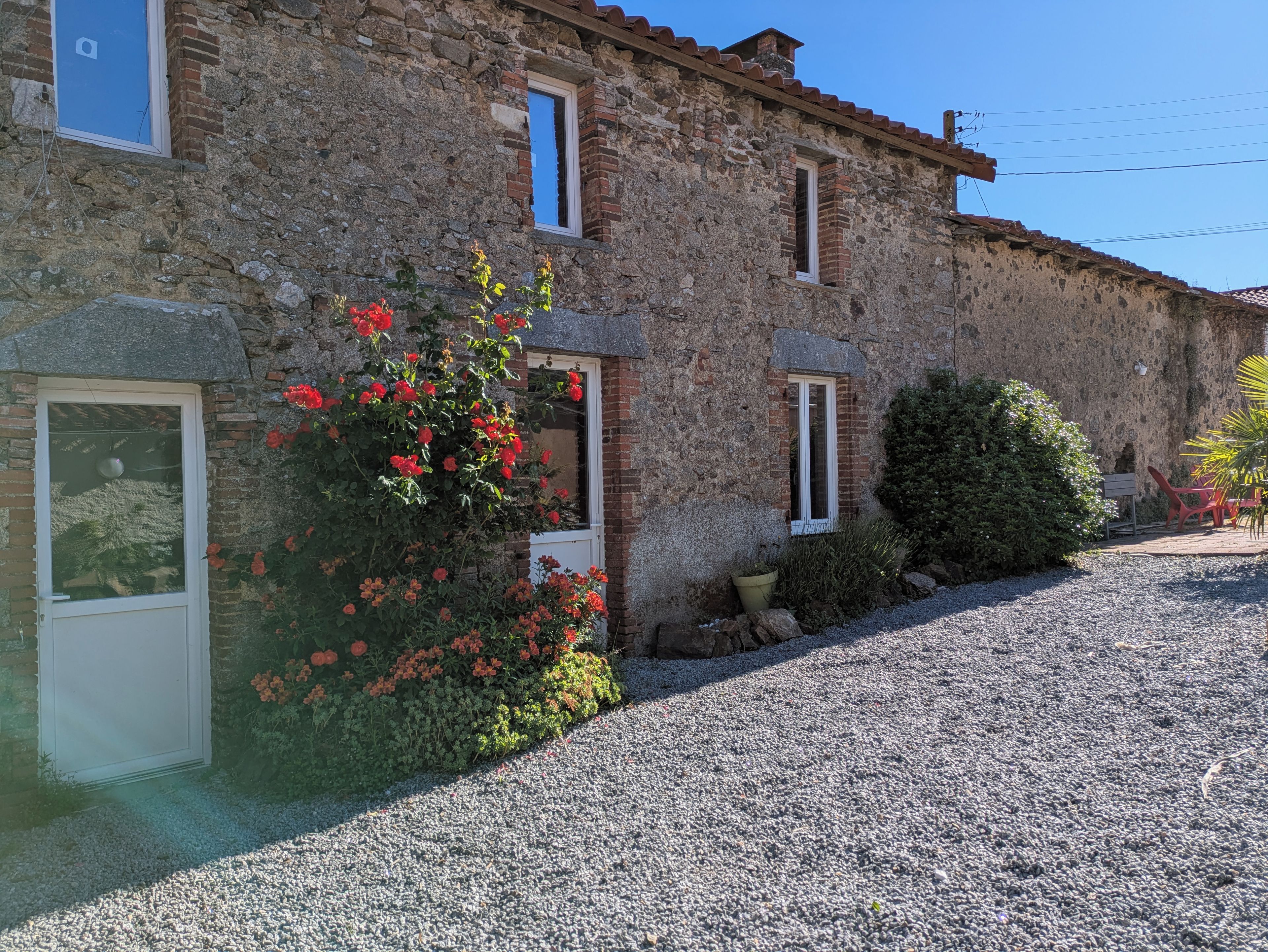 A stone building with multiple windows and a gravel driveway.