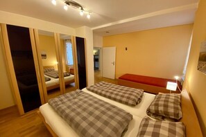 Habitación de hotel con cama, un banco rojo y un armario con puertas correderas.