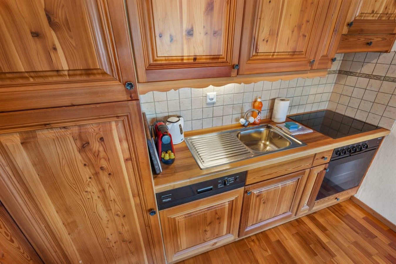 Une cuisine avec des meubles en bois, un évier en acier inoxydable, un lave-vaisselle et une cuisinière.