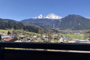 Eine Berglandschaft mit einem Dorf im Vordergrund und schneebedeckten Gipfeln im Hintergrund.