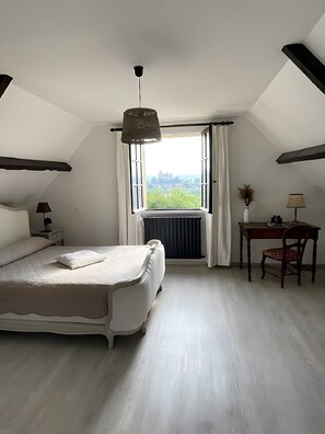 Une chambre à coucher comprenant un lit, un bureau, une chaise, une fenêtre avec des rideaux et un luminaire suspendu.